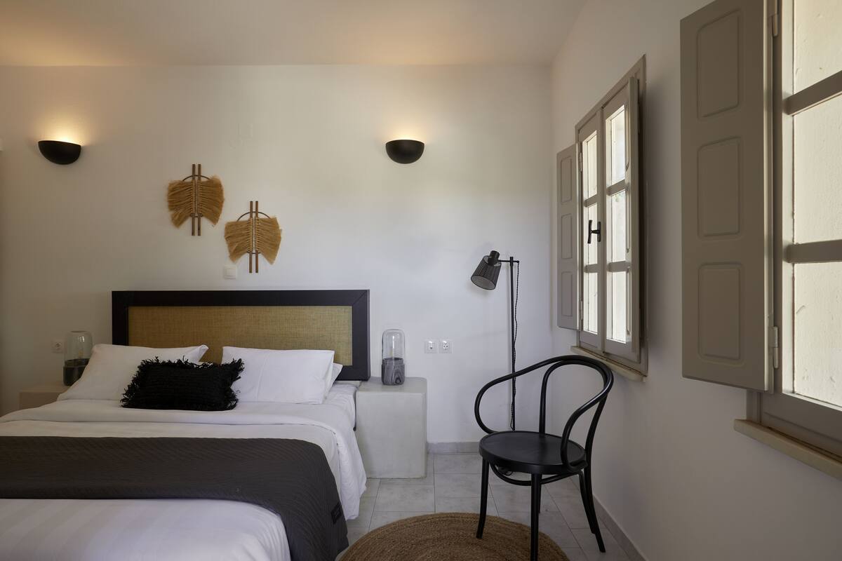 A bedroom with a bed, bedside lamps, a chair, and a window.