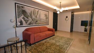 A modern living room with a red sofa, a patterned rug, and a large wall painting.