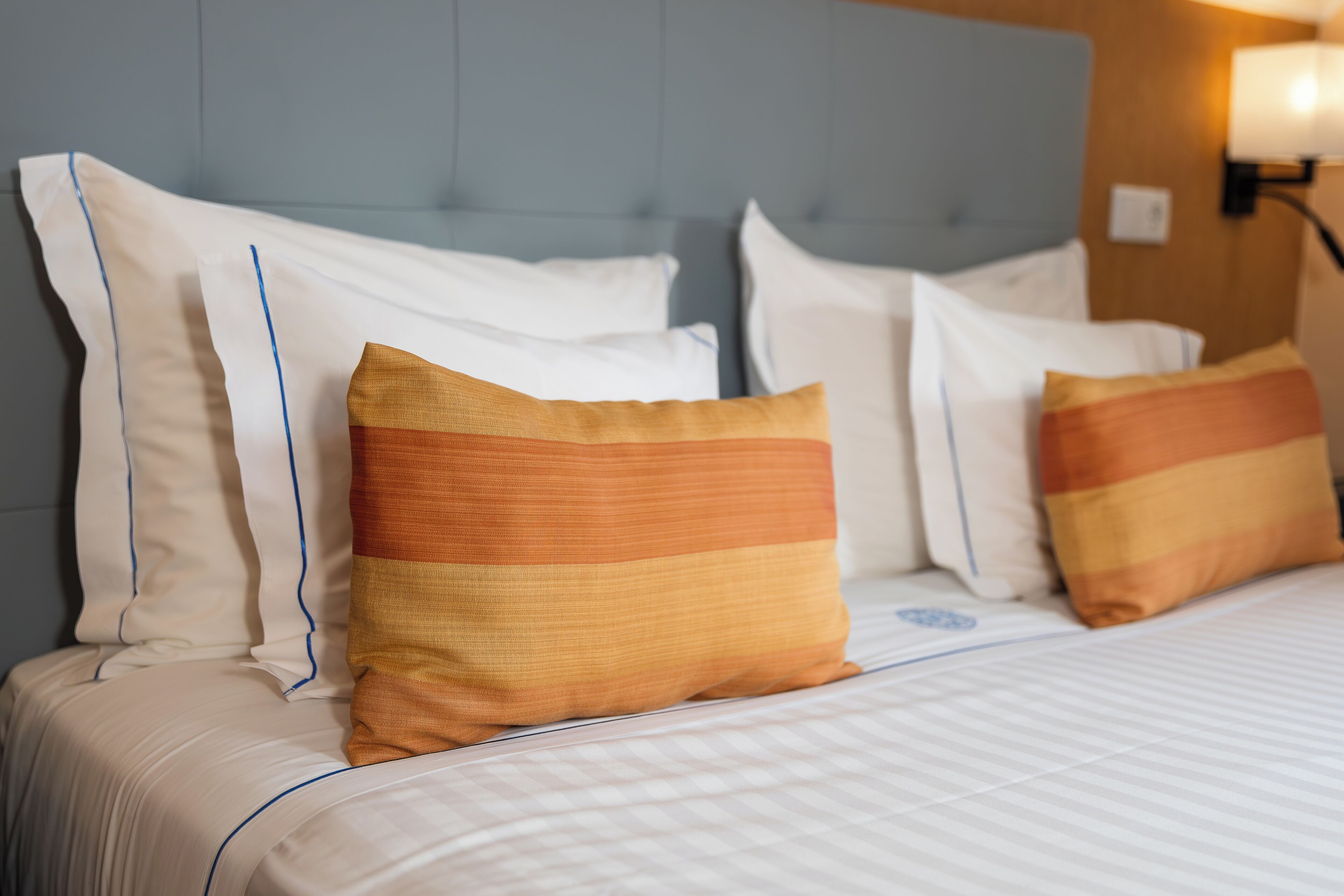 A neatly made bed with white linens and striped pillows.