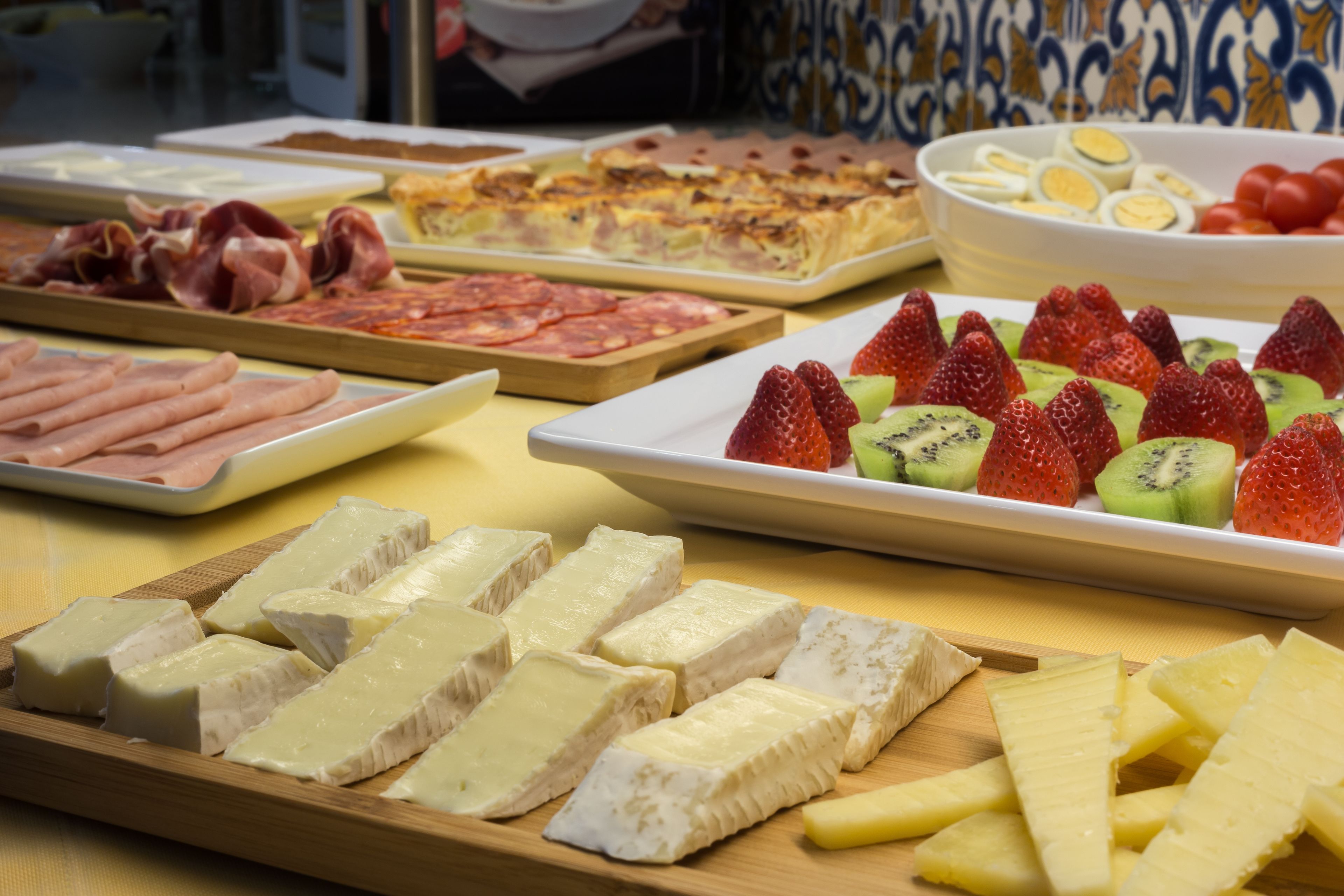A buffet with various cheeses, fruits, and meats.