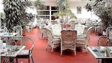 An outdoor dining area with wicker furniture and potted plants.