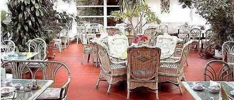 An outdoor dining area with wicker furniture and potted plants.