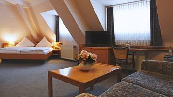 Una habitación de hotel con cama, escritorio, silla, mesa y televisor.
