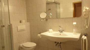 Un baño con inodoro, lavamanos y cabina de ducha de vidrio.