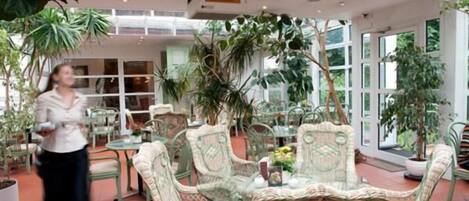 Un jardín interior con mobiliario de mimbre y plantas en macetas.