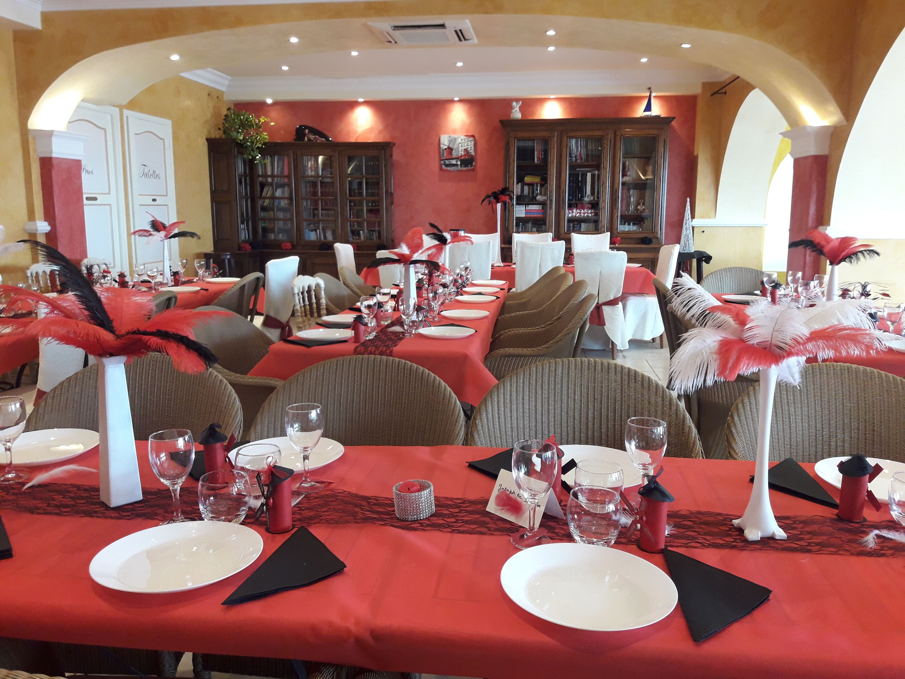 Un restaurant avec des nappes rouges, des chaises blanches et des décorations à base de plumes.