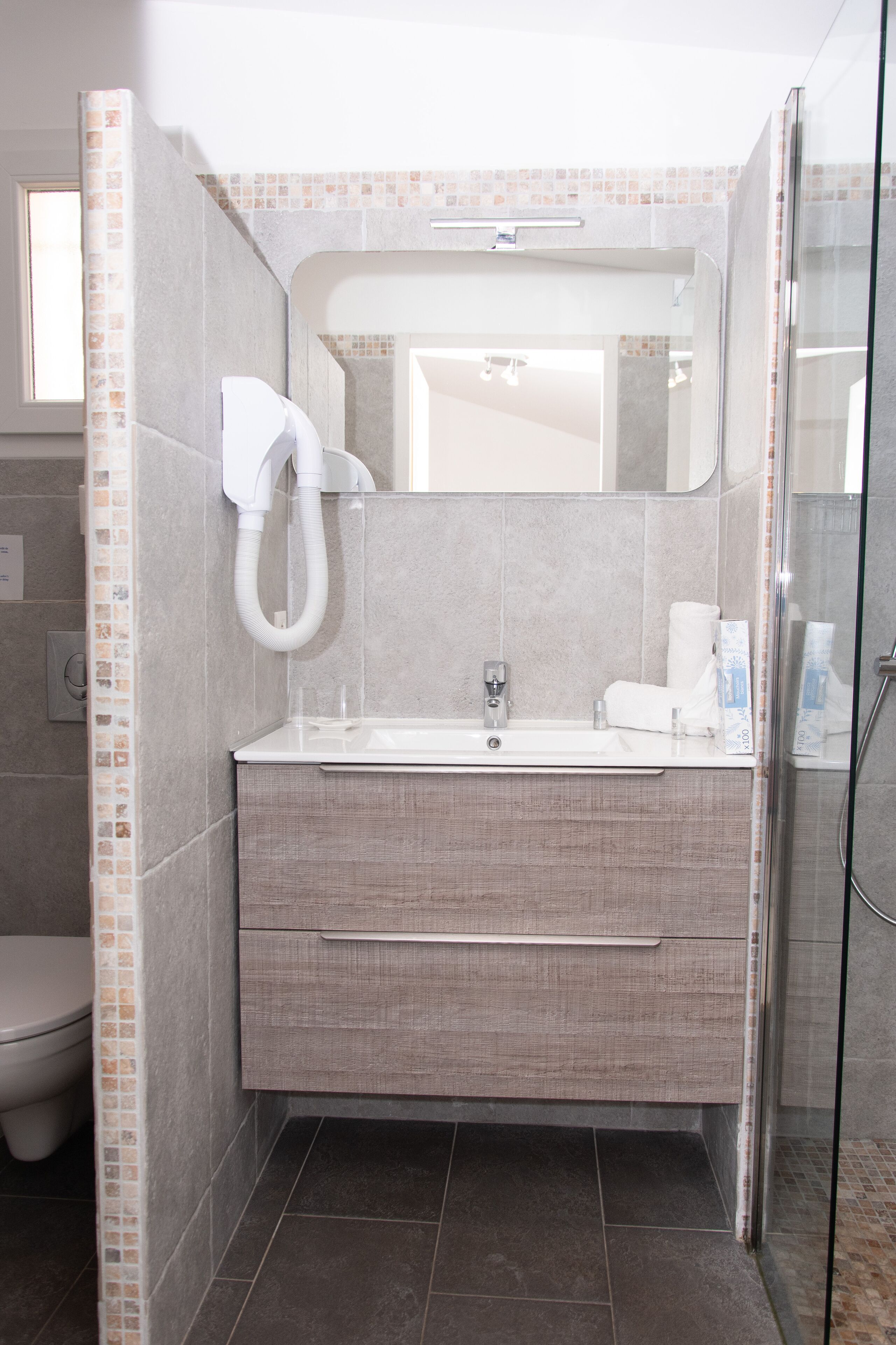 Une salle de bain moderne dotée d’une douche à parois de verre, d’un lavabo intégré et d’un miroir au-dessus du meuble-lavabo.