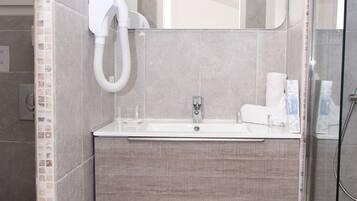 Une salle de bain moderne dotée d’une douche à parois de verre, d’un lavabo intégré et d’un miroir au-dessus du meuble-lavabo.