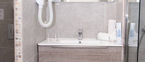 A modern bathroom with a glass shower enclosure, a built-in sink, and a mirror above the vanity.