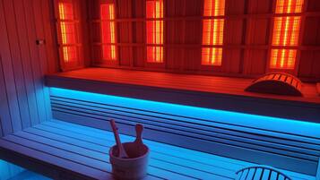 Un sauna avec des bancs en bois et un banc muni d’un seau et de louches.
