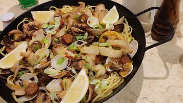 Un plat de pâtes aux fruits de mer, garni de rondelles de citron et d’oignons verts.