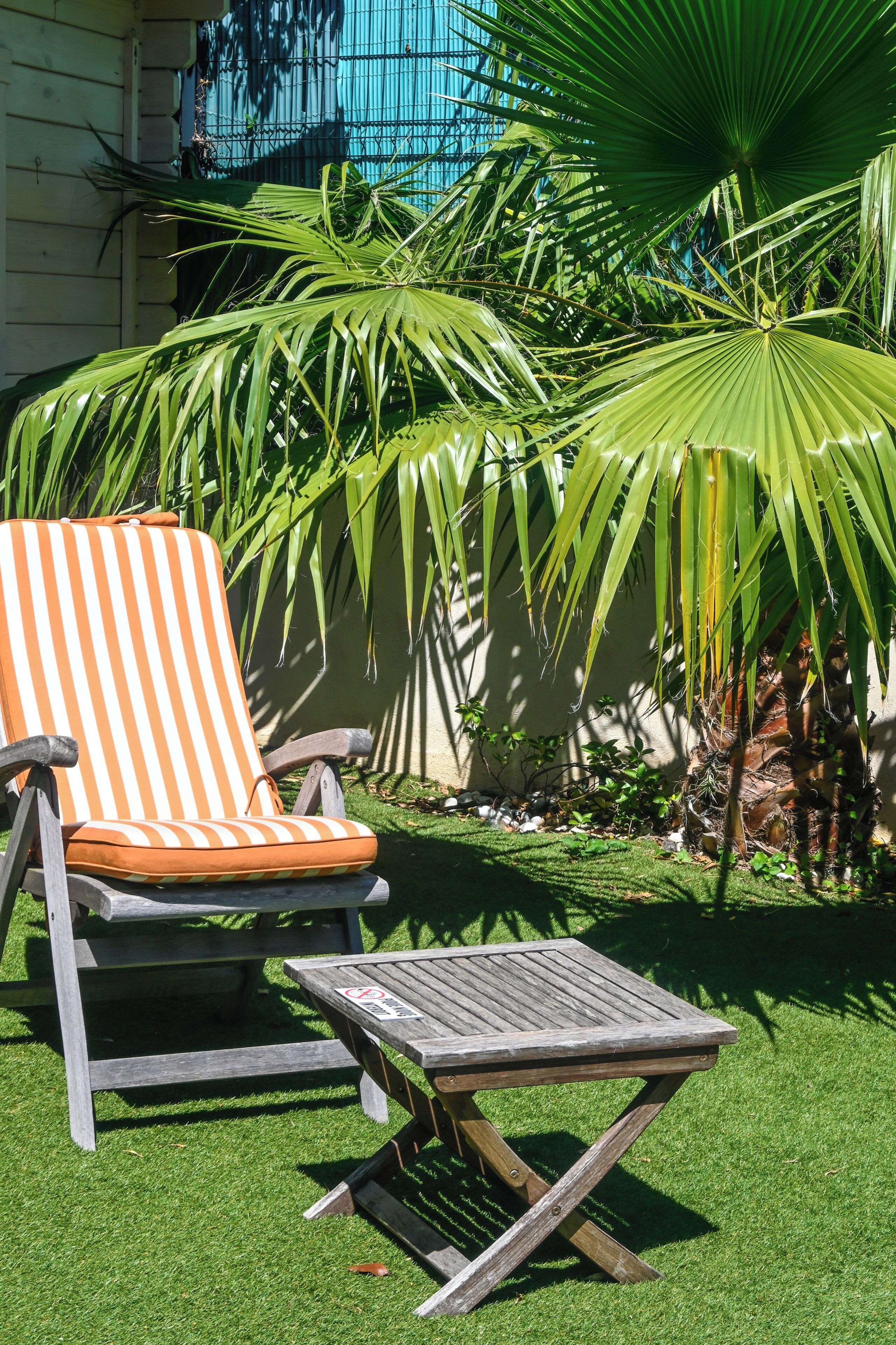 Un espace patio avec une chaise longue à rayures et une petite table en bois.