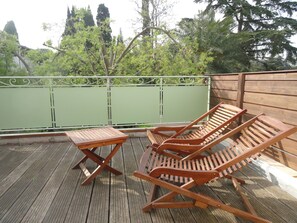 Eine Holzterrasse mit einem Tisch und zwei Liegestühlen.