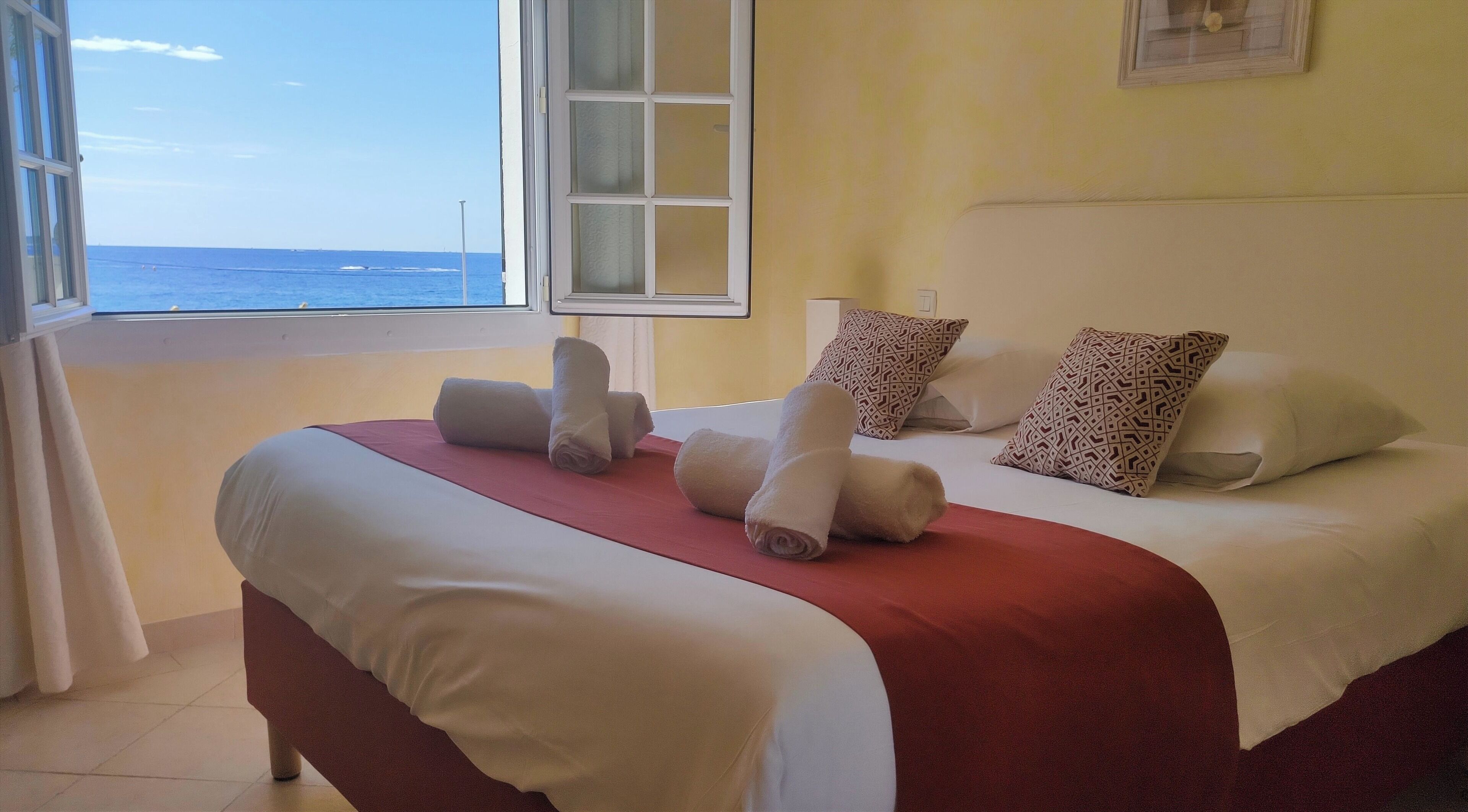 Una habitación de hotel con una cama, almohadas y vista al océano.