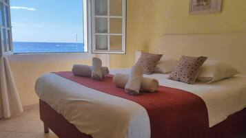Una habitación de hotel con una cama, almohadas y vista al océano.