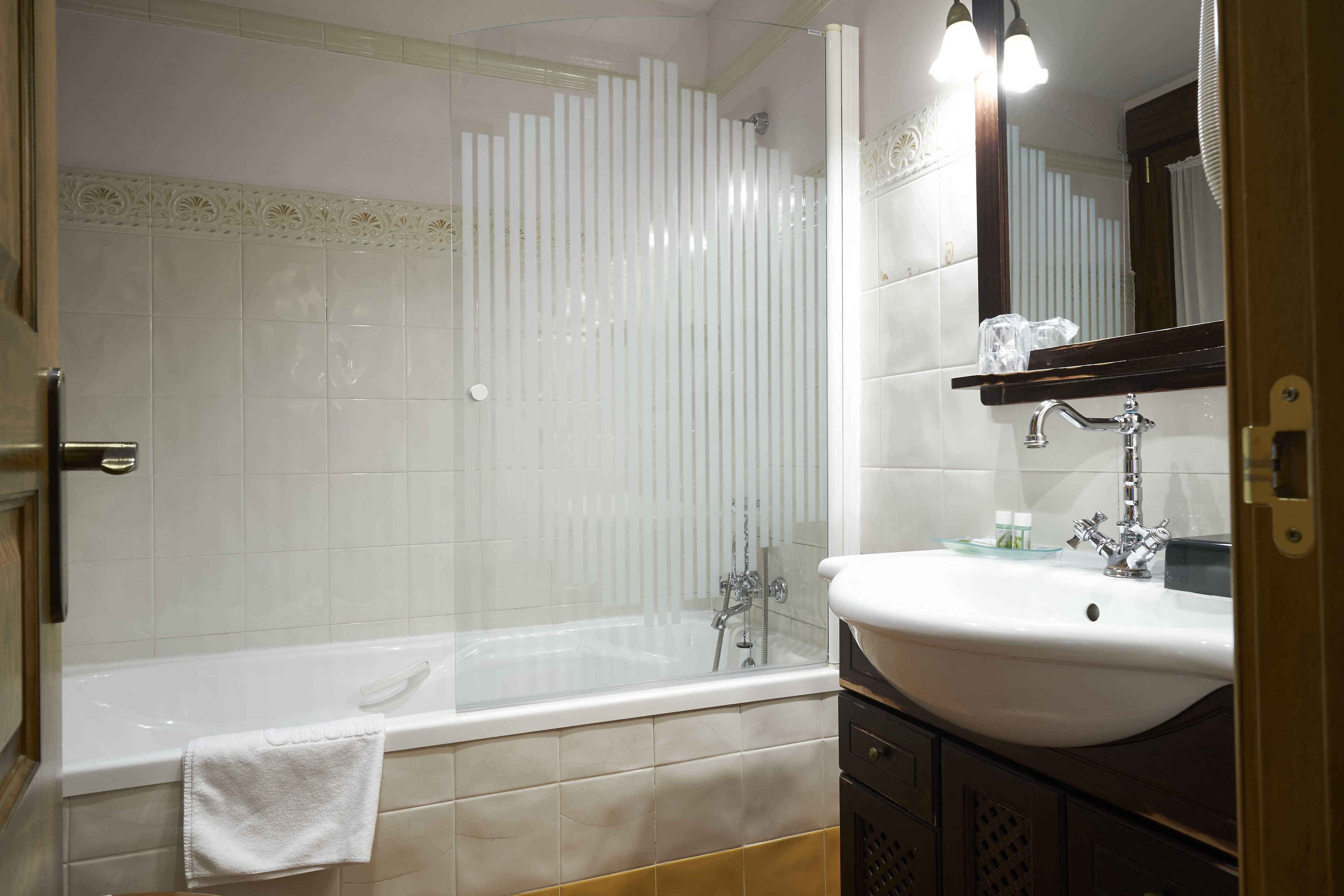 Un baño con bañera, lavamanos y espejo.