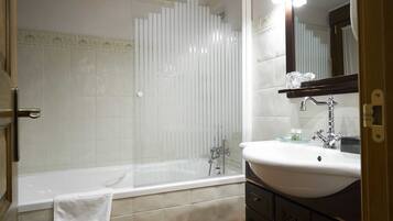 Un baño con bañera, lavamanos y espejo.