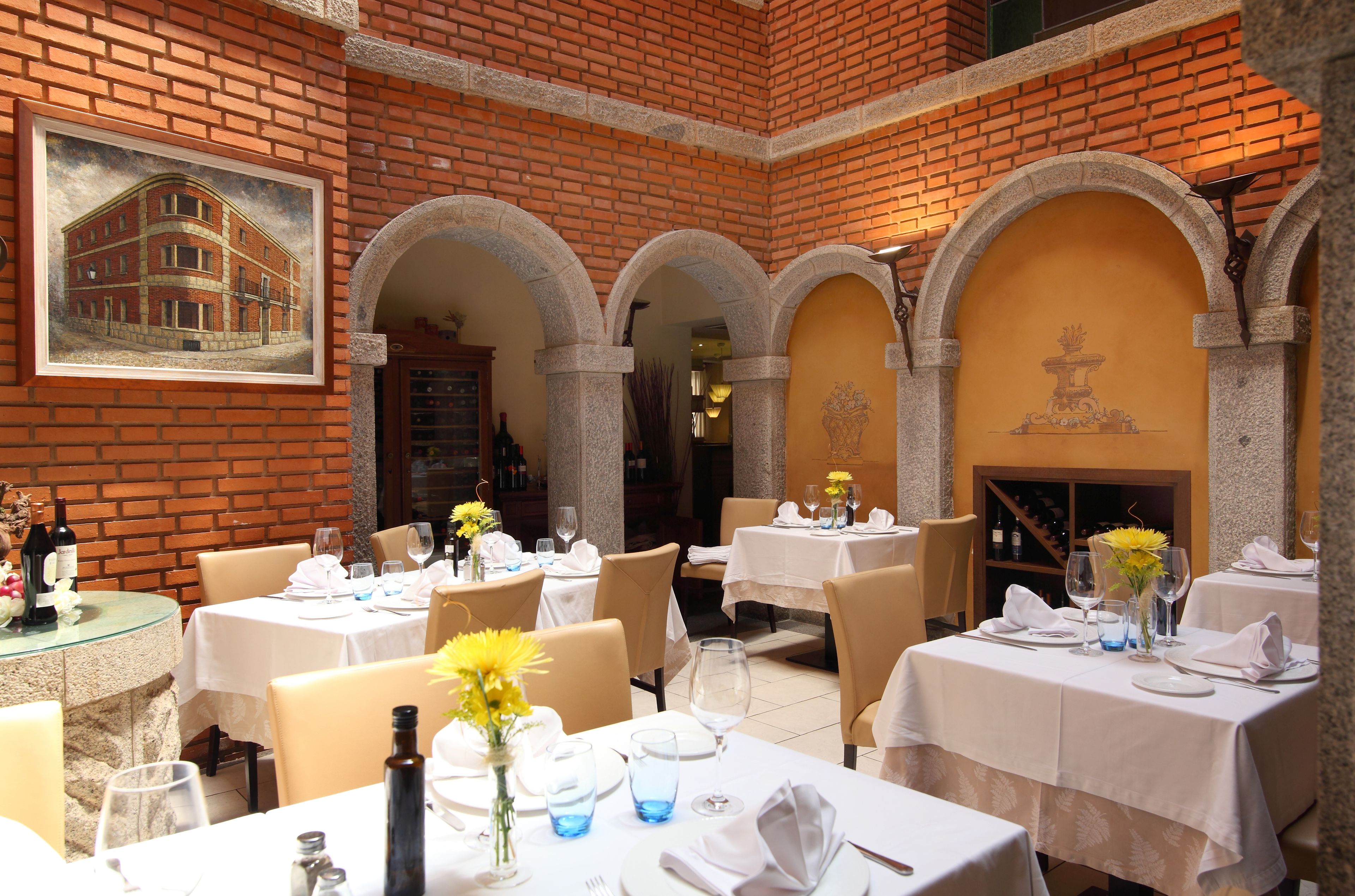 Un restaurante con paredes de ladrillo, mesas blancas y flores amarillas.