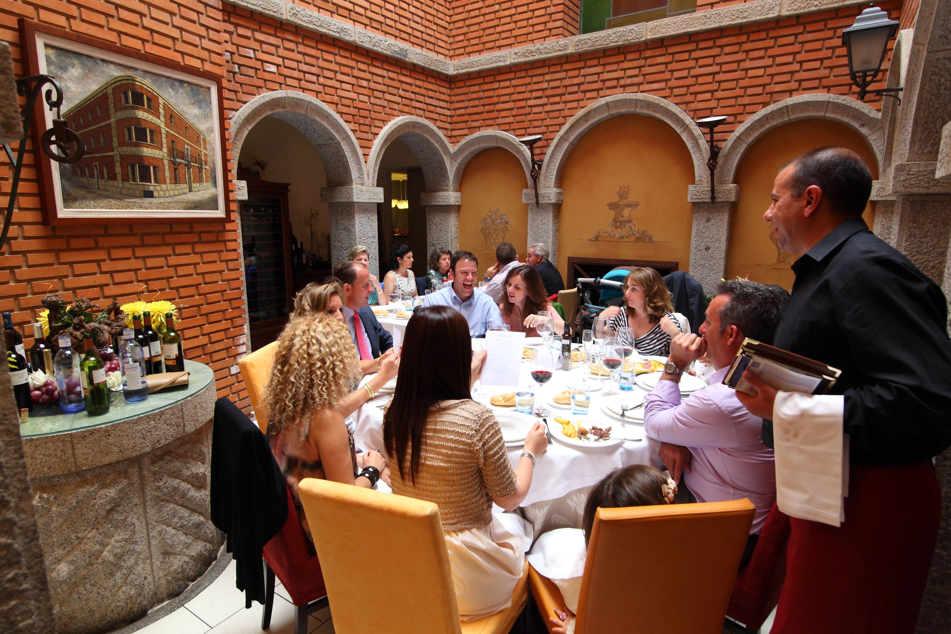 Un grupo de personas cenando en un restaurante al aire libre con paredes y arcos de ladrillo.