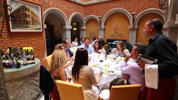 Un grupo de personas cenando en un restaurante al aire libre con paredes y arcos de ladrillo.