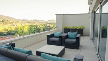 A balcony with wicker furniture, a glass door, and potted plants.