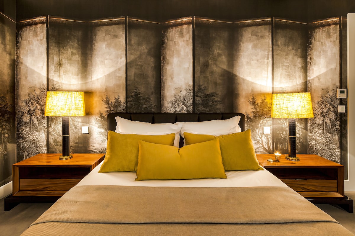 A hotel room with a large bed, two nightstands, and a wall with a textured design.
