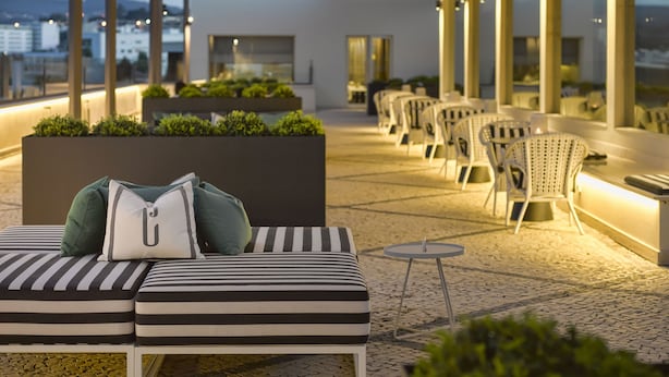 Terraza en la azotea con zona de estar, cojines a rayas y una mesita.