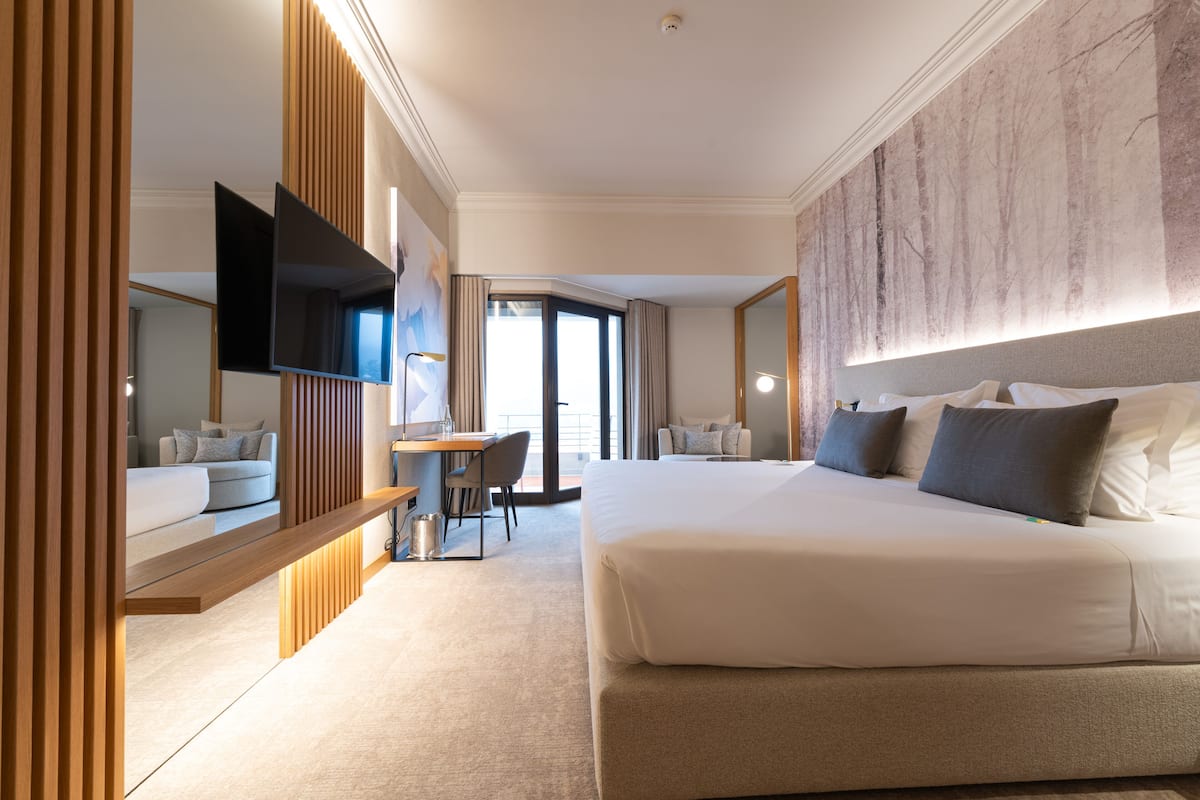 A modern hotel room with a large bed, a desk, and a TV.