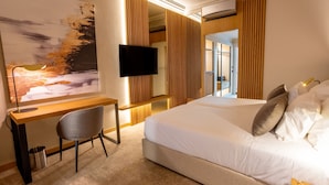 Habitación de hotel con cama, escritorio, silla, televisión y un cuadro grande en la pared.