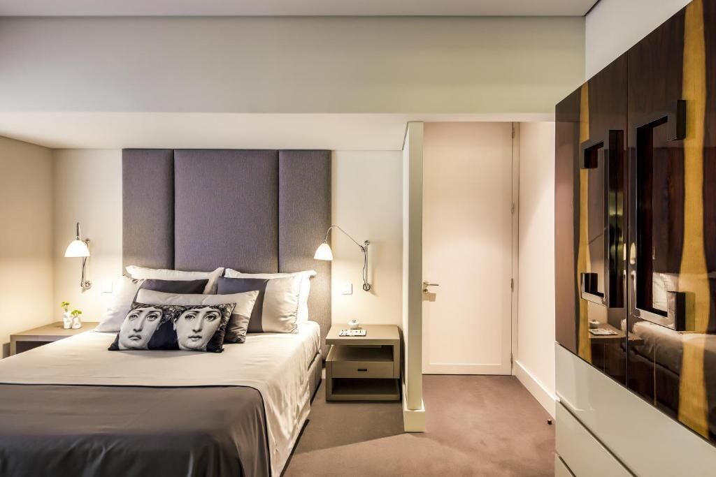 Una habitación de hotel moderna con una cama grande, lámparas de noche, una mesita de noche y un armario.