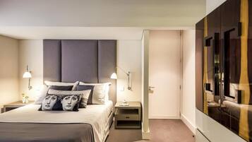 Una habitación de hotel moderna con una cama grande, lámparas de noche, una mesita de noche y un armario.