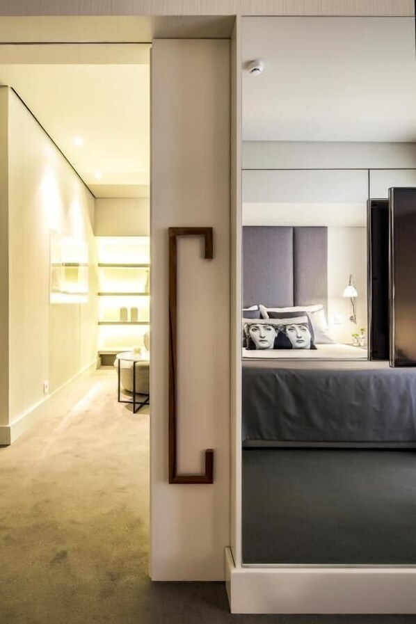 A modern hotel room with a large bed, a bedside table, and a nightstand. There is a view into the adjacent room, which has a similar bed and a lamp. - Cidnay - Hotel & Executive Center (Santo Tirso)