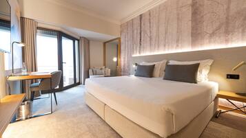 A spacious hotel room with a large bed, a desk, and a chair.