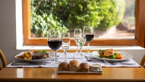 Una mesa de comedor con platos de comida, copas de vino y panes.