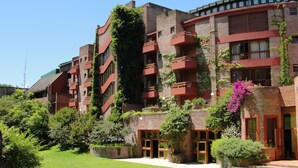 Un edificio de varios pisos con paredes de ladrillo, balcones y un jardín con diversas plantas y flores.