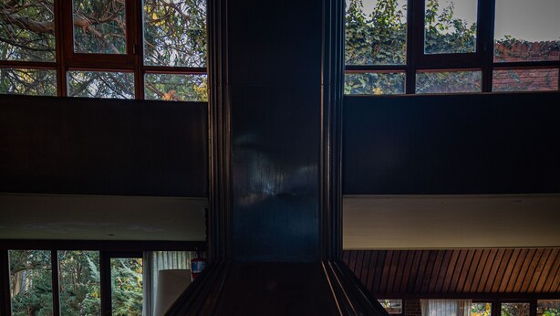 Una habitación acogedora con chimenea, dos sillones, una mesa de centro y vistas al exterior a través de amplios ventanales.