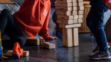 Una habitación con un ventanal grande, una estructura de madera que recuerda a un juego, y un niño jugando.