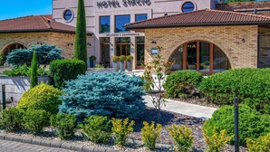 A hotel with a modern facade, arched windows, and a well-maintained garden.