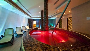 A spa area with a hot tub, seating, and a patterned wall.