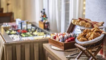 Buffet com diversos alimentos, incluindo doces e acompanhamentos, dispostos em mesas de madeira.