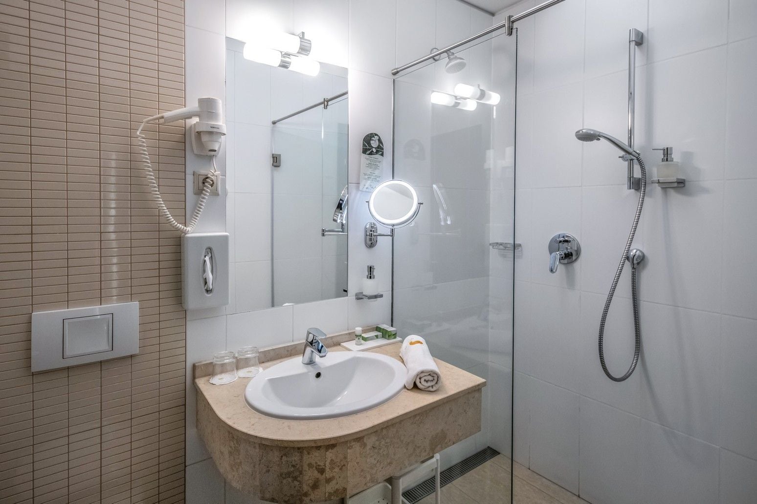 A modern bathroom with a sink, mirror, and glass shower enclosure.