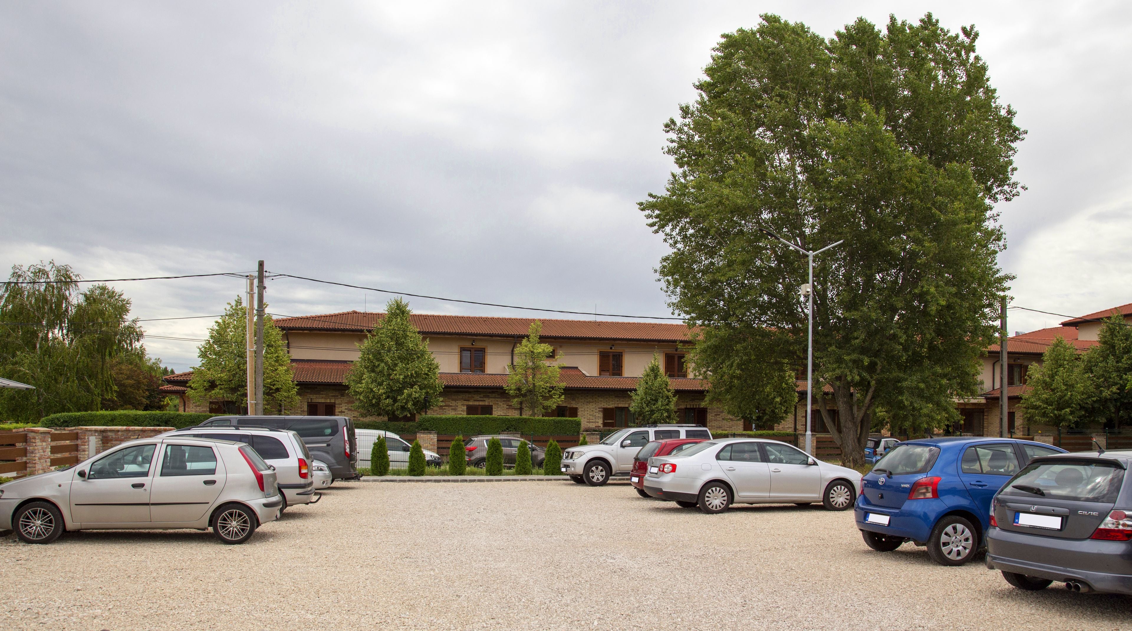 A parking lot with several cars and a building with a red roof in the background.