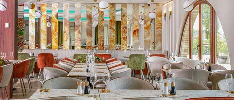A restaurant with a long dining table, multiple chairs, and a modern interior design.