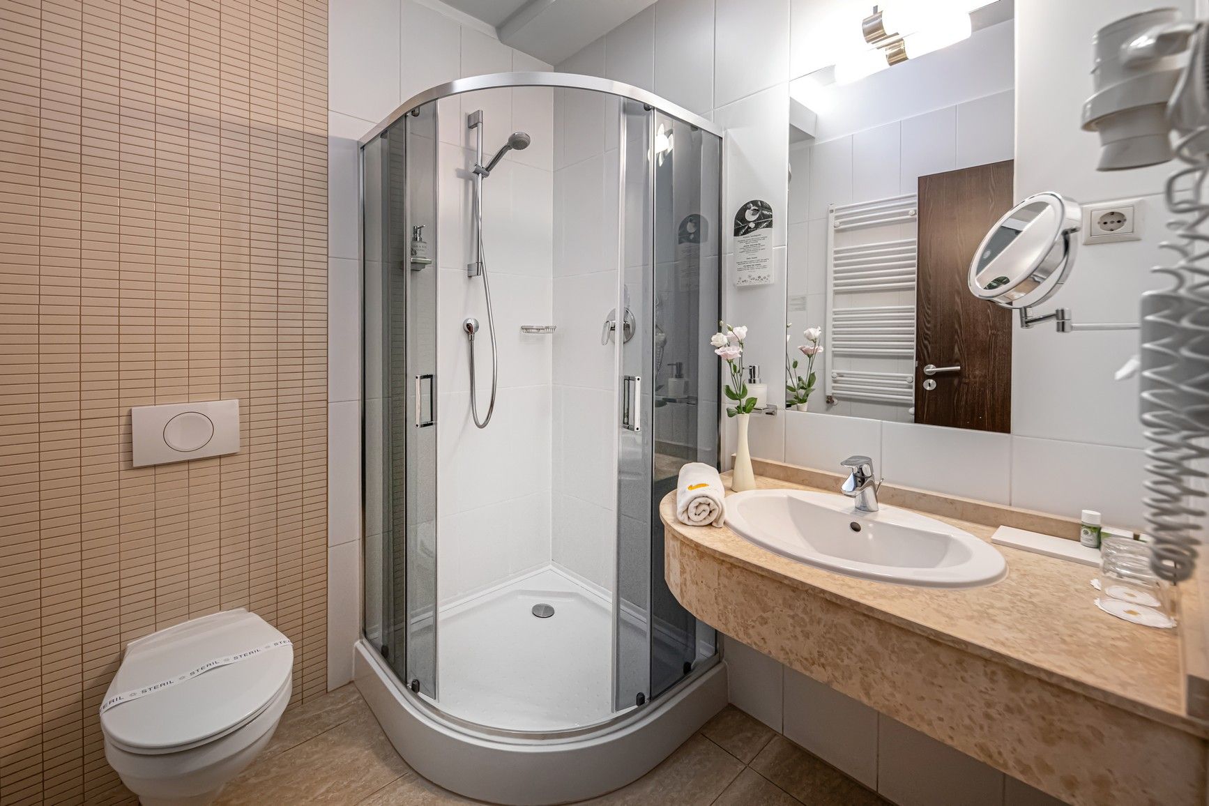 Un baño moderno con ducha envuelta en vidrio, inodoro blanco y tocador con espejo.