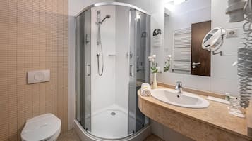 Un baño moderno con ducha envuelta en vidrio, inodoro blanco y tocador con espejo.