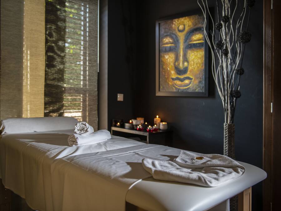 A spa room with a massage table, candles, and a wall painting.