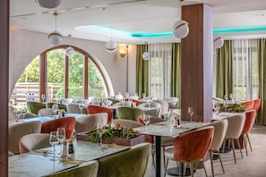 Un restaurante con mesas redondas, sillas e iluminación colgante.