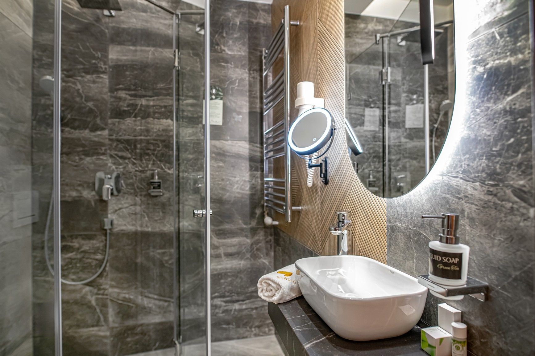 A modern bathroom with a glass shower enclosure, a large mirror, and a white sink.