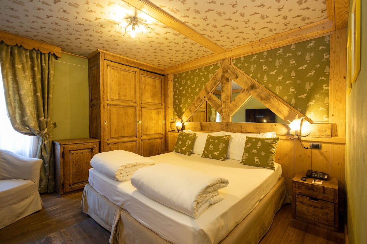 Un dormitorio acogedor con una cama grande, cabecera de madera y una mesita de noche con lámpara.