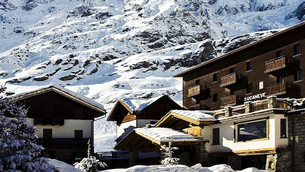 Una montaña cubierta de nieve con un edificio de madera que dice 'BUCANEVE' al frente.